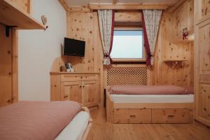 1 dormitorio con 2 camas, TV y ventana en Residence Nagler - BelaVal Apartments, en Badia