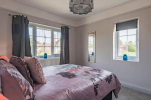 a bedroom with a bed and two windows at 19th Hole in Sandwich