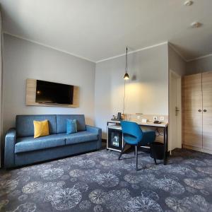 a living room with a blue couch and a desk at Hotel Purucker in Kulmbach