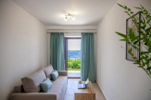 AGIOS PETROS APARTMENTS في Ágios Pétros: غرفة معيشة مع أريكة ونافذة كبيرة