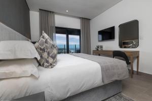 a bedroom with a bed and a desk and a television at 2202 Oceans Apartment - by Stay in Umhlanga in Durban