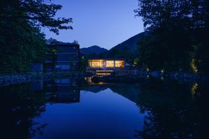 Jozankei的住宿－Okujozankei Onsen Kasho Gyoen，夜晚坐在河边的房子