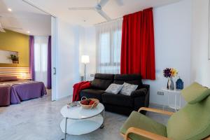 - un salon avec un canapé et une table dans l'établissement Sevilla Central Suites Apartamentos Puerta Jerez, à Séville