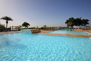 a large pool of blue water with trees in the background at Anezi Apartments in Agadir
