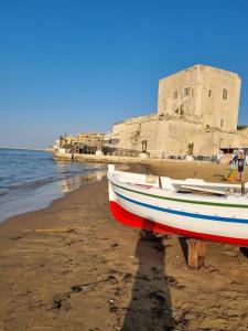 un bateau sur la plage avec un château en arrière-plan dans l'établissement Pietre Nere House, à Pozzallo