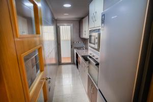 une petite cuisine avec des placards blancs et un couloir dans l'établissement PISO SAN ISIDRO (ALICANTE), à Alicante