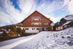 un gran edificio de madera con nieve delante en Apartments Telemark Kranjska Gora, en Kranjska Gora