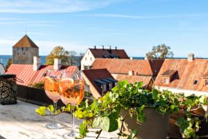 two glasses of wine sitting on a balcony with a city at Best Western Strand Hotel in Visby