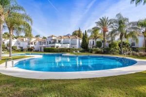 einen großen Pool in einem Garten mit Palmen in der Unterkunft OleHolidays Señorío Gonzaga junto a Puerto Banús in Marbella