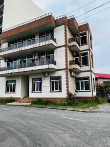 ein großes weißes Gebäude mit Balkon auf einer Straße in der Unterkunft Apartments NITA in Batumi