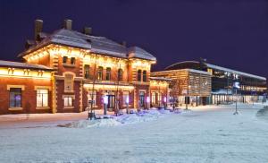 un edificio iluminado en la nieve por la noche en Lillehammer Stasjonen Hotel en Lillehammer