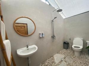 a bathroom with a sink and a mirror and a toilet at Rejeng Garden Camp in Bangli