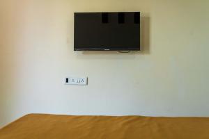 einen Flachbild-TV, der an einer weißen Wand hängt in der Unterkunft Anandvan Beach Resort in Alibag