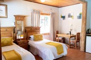 a room with two beds and a table and a desk at Sunbird Lodge in Phalaborwa