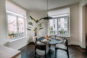 a dining room with a table and chairs and two windows at Sud d'Anvers in Antwerp