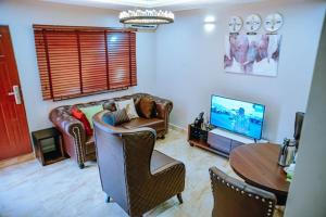 a living room with a couch and a tv at House 7 Mbora 2 Bedroom Luxury apartment A home away from home Jabi Near Wuse 2 Abuja Fully Serviced Wifi and More in Abuja