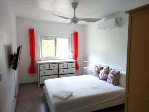 a bedroom with a bed and a window with red curtains at SolyViento 67 in Cabarete