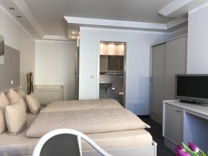 Schlafzimmer mit einem Bett und einem Schreibtisch mit einem TV in der Unterkunft Pension Villa Transvaal in Ahlbeck
