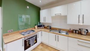 a kitchen with white cabinets and a green wall at Apartment 332 in Hull