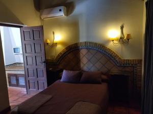 Schlafzimmer mit einem Bett, einer Tür und Beleuchtung in der Unterkunft DEHESA LAS BRIDAS, SL in Morón de la Frontera