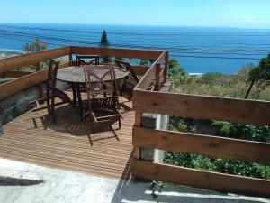 una terraza de madera con mesa, sillas y el océano en case ti kaf, en Saint-Leu