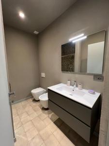 uma casa de banho com um lavatório, um WC e um espelho. em LE MONGOLFIERE em Cuneo