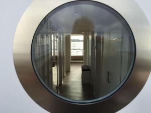 a round mirror on a wall in a hallway at Hausboot ANTARES ONE by Seeblick Ferien ORO in Olpenitz