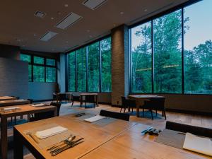 Okujozankei Onsen Kasho Gyoen في Jozankei: قاعة اجتماعات مع طاولات وكراسي ونوافذ كبيرة