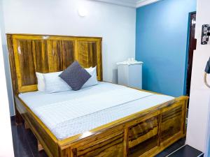 Cama de madera en habitación con paredes azules en Golden Touch Executive Hotel en Tema