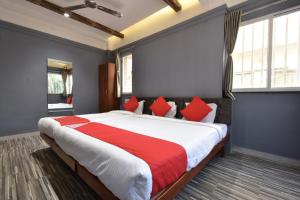 索拉普的住宿－Hotel Ashirwad, Solapur，一间卧室配有一张带红色和白色枕头的大床