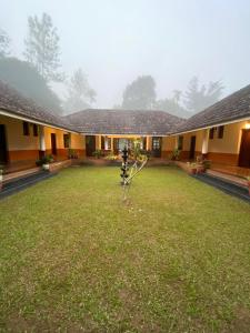 a house with a yard with a tree in the yard at 3 Hills Hostel in Wayanad