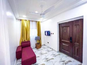 uma sala de estar com uma porta e um sofá vermelho em Golden Touch Executive Hotel em Tema