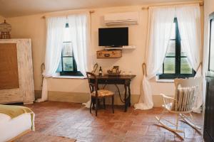Schlafzimmer mit einem Schreibtisch, einem TV und Fenstern in der Unterkunft Locanda in Tuscany in Castiglione dʼOrcia