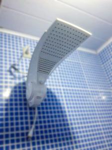 uma cabeça de chuveiro numa casa de banho com azulejos azuis em Pousada Canto das Araras - Vila Bom Jardim Nobres MT em Nobres