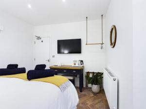 a bedroom with a bed and a desk with a tv at Driftwood Boutique Guest House in Rhosneigr