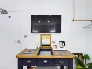 a desk in a room with a tv on the wall at Driftwood Boutique Guest House in Rhosneigr