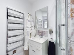 a white bathroom with a sink and a mirror at Driftwood Boutique Guest House in Rhosneigr