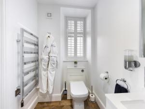 a white bathroom with a toilet and a window at Driftwood Boutique Guest House in Rhosneigr