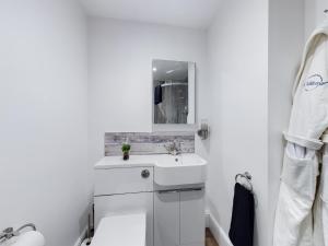 a white bathroom with a sink and a mirror at Driftwood Boutique Guest House in Rhosneigr