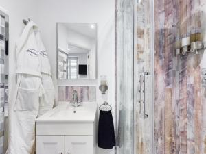 a white bathroom with a sink and a shower at Driftwood Boutique Guest House in Rhosneigr