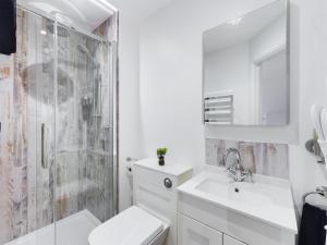 a white bathroom with a sink and a shower at Driftwood Boutique Guest House in Rhosneigr