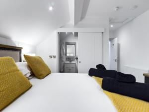 a bedroom with a large white bed and yellow pillows at Driftwood Boutique Guest House in Rhosneigr