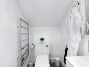 a white bathroom with a toilet and a sink at Driftwood Boutique Guest House in Rhosneigr