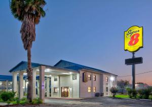 a motel with a sign and a palm tree at Super 8 by Wyndham Victoria - South - Hwy 59 in Victoria