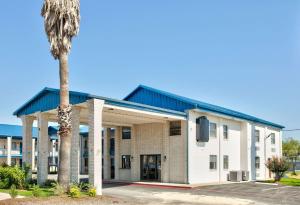 a building with a palm tree in front of it at Super 8 by Wyndham Victoria - South - Hwy 59 in Victoria