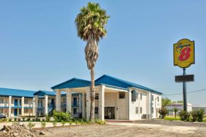 a hotel with a palm tree in front of it at Super 8 by Wyndham Victoria - South - Hwy 59 in Victoria