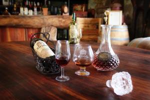 Dois copos de vinho e uma cesta de garrafas de vinho numa mesa de madeira em Bezalel Wine & Brandy Estate em Kanoneiland