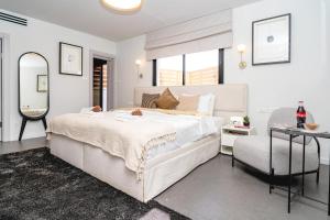 a white bedroom with a large bed and a chair at New Duplex 3 Bedroom with Jacuzzi in Tel Aviv