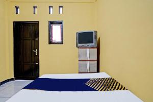 a room with a bed and a tv and a door at OYO Life 91947 Kost Barokah Syariah in Mojokerto