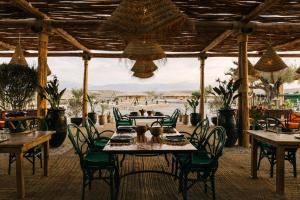 a restaurant with tables and chairs and a view of the beach at Caravan Agafay by Our Habitas in Marrakesh